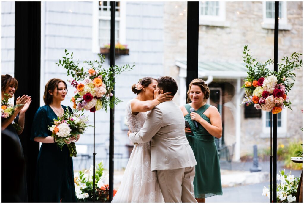 The brides share their first kiss during their wedding ceremony at the Sinclair of Skaneateles.