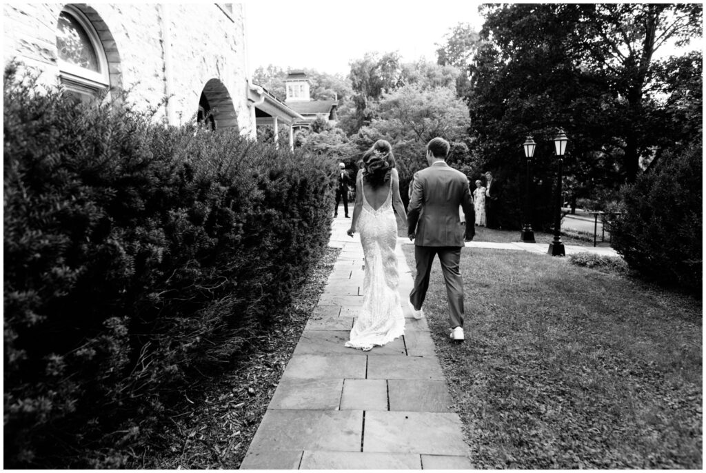 A black and white photo of the bride and groom walking away towards their family after their first look in Ithaca, NY.