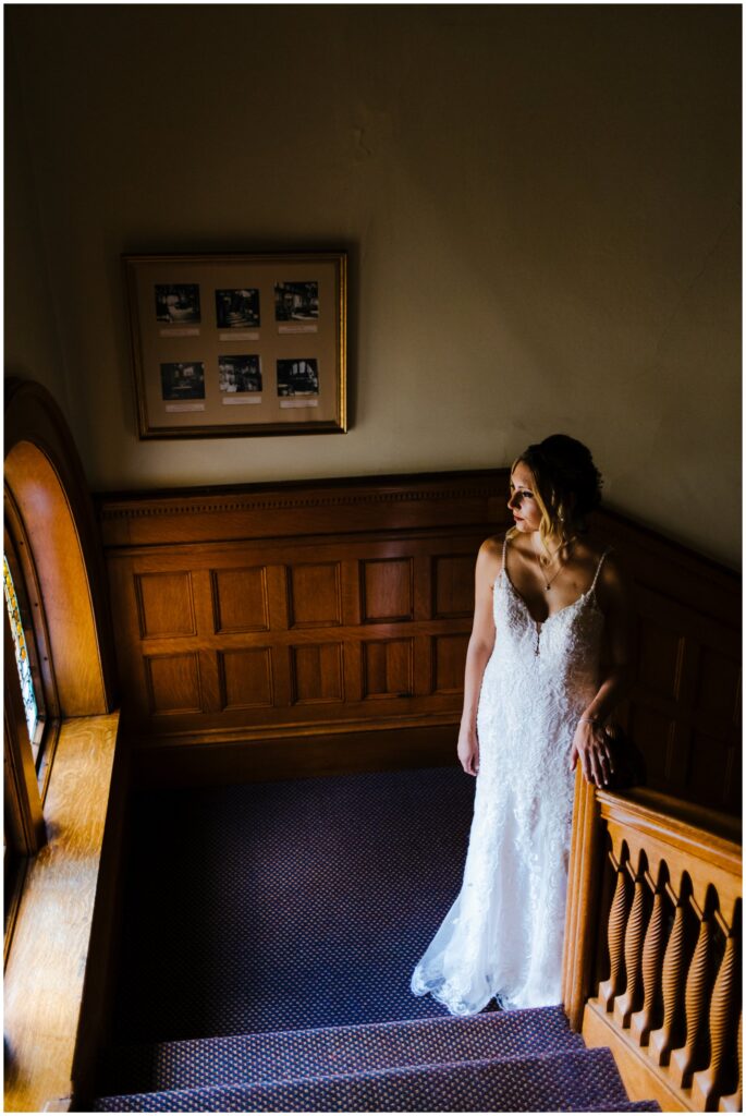 A bride gazes out the window on the 2nd floor of belhurst castle.