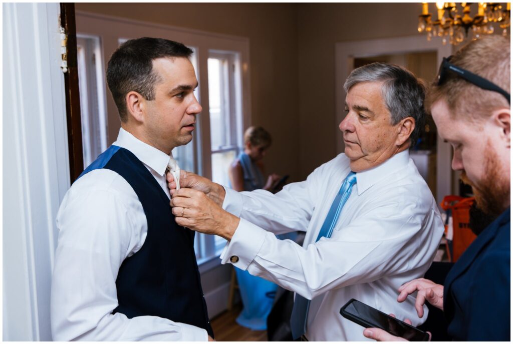 the father of the groom adjusts the grooms tie.