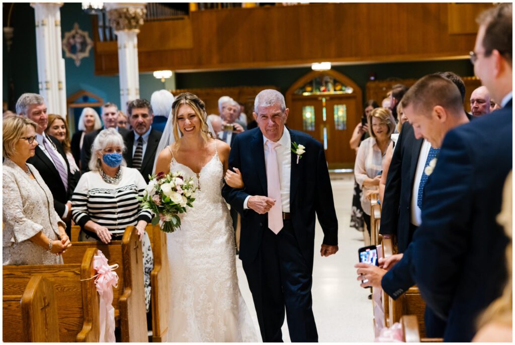 a bride and her father walk down the aisle together.