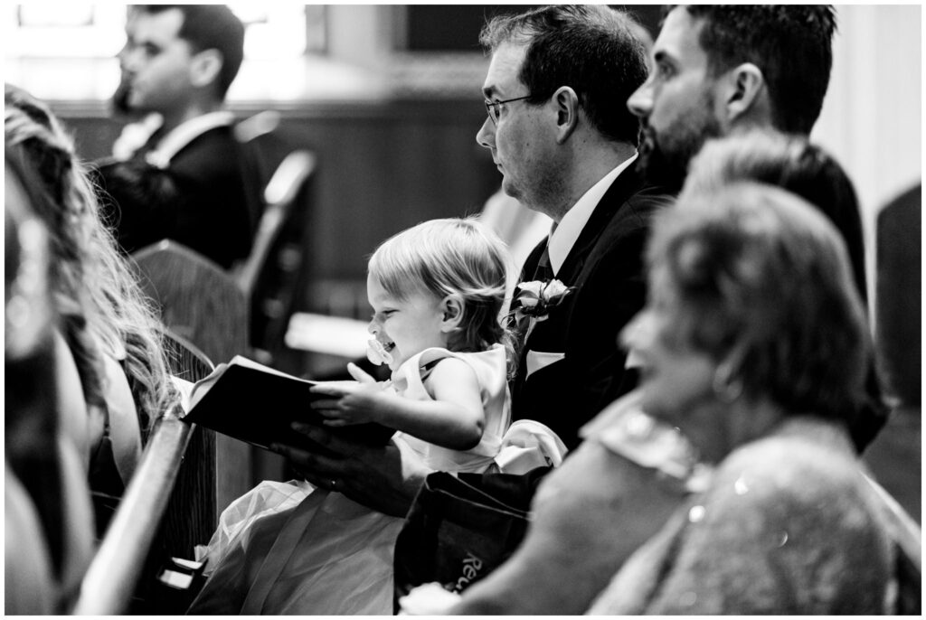 a small child smiles during a wedding ceremony at St. Patrick's church in Syracuse, NY.