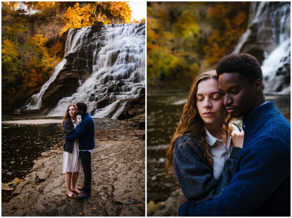 Couple snuggles together during their ithaca engagement session, a waterfall is behind them.