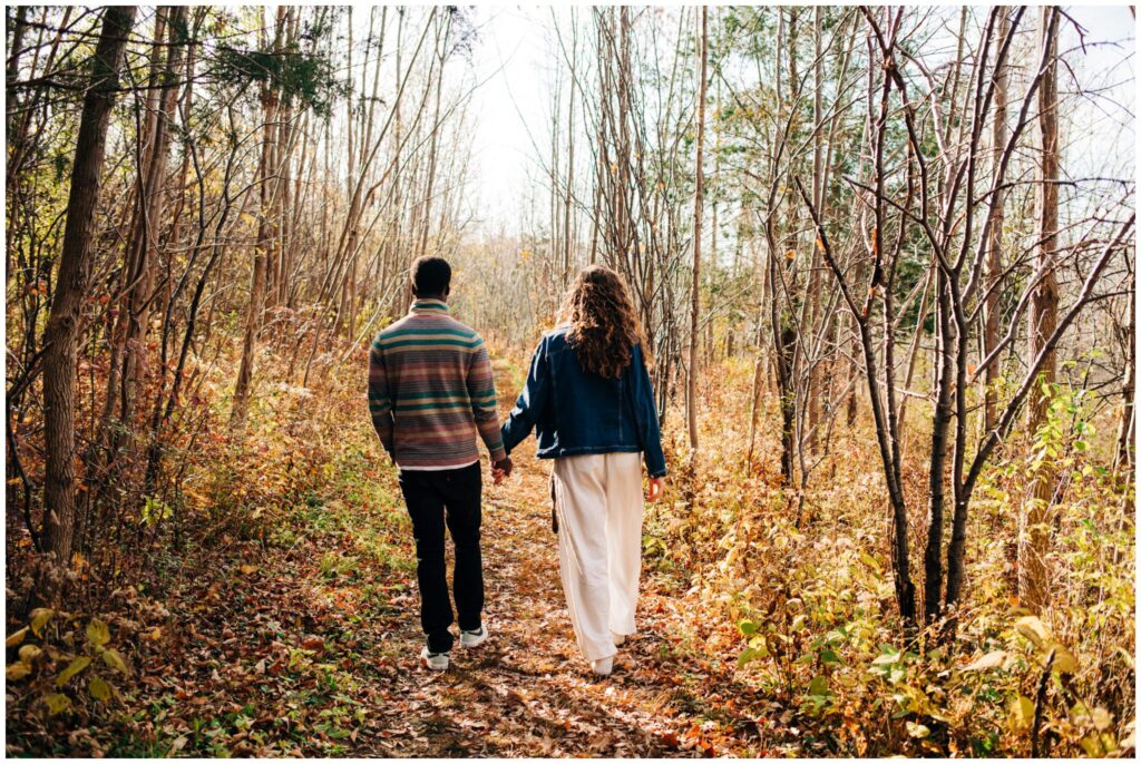 Couple walks away from each other holding hands during their documentary style engagement session.