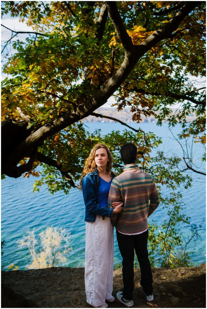Guy looks at water while woman looks into the distance during their engagement session.