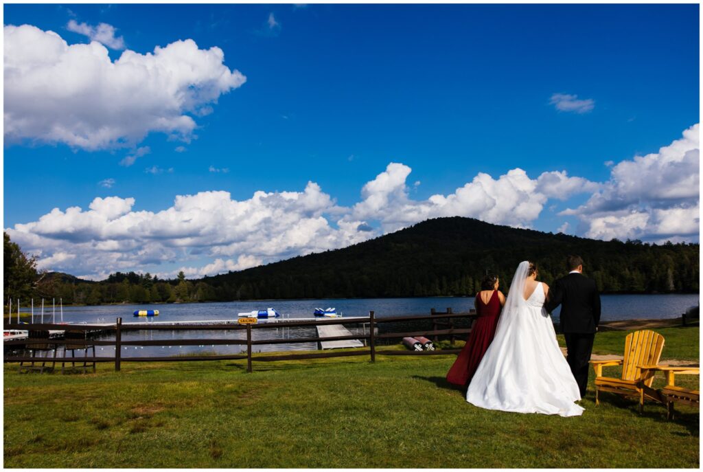 Bride is escorted by her parents during her wedding ceremony in the adirondacks of New York.