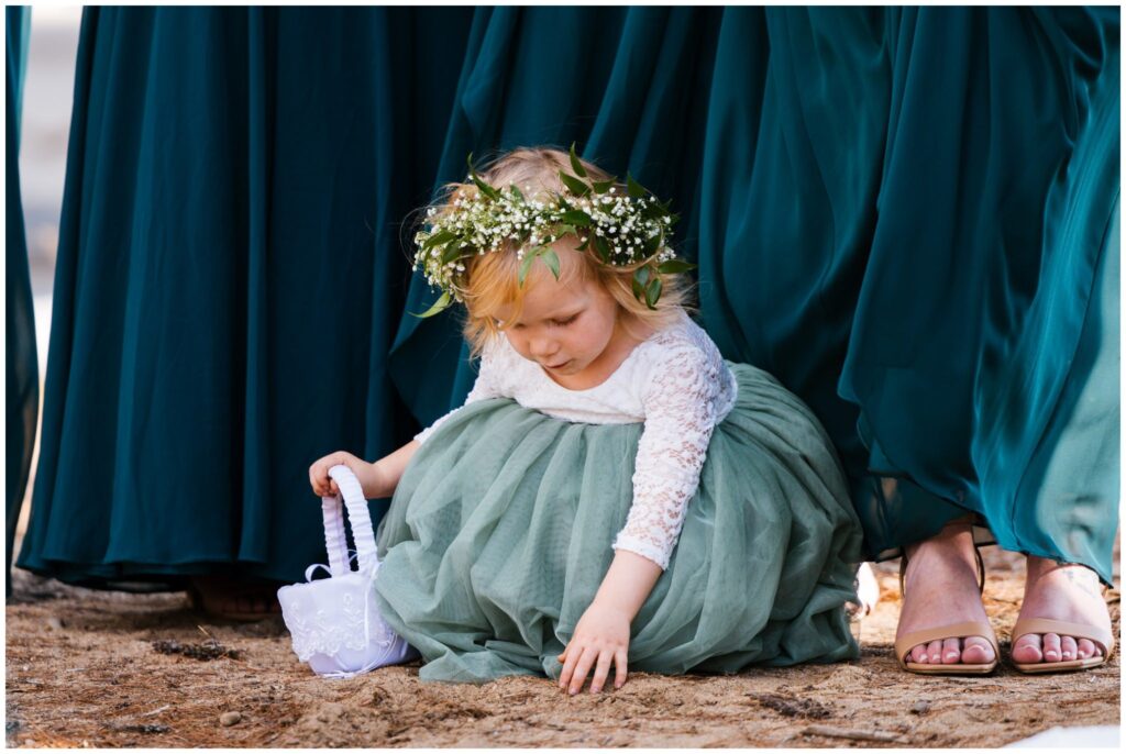 Flower girl plays in the sand during wedding ceremony.