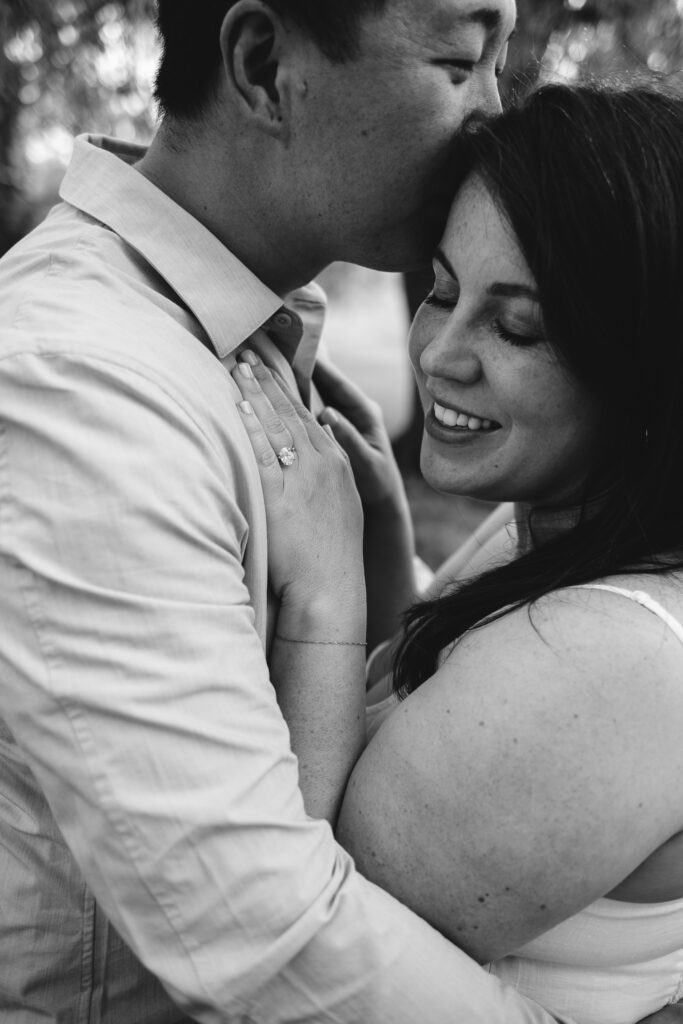 Black and white image of a couple close together. It is an engagement session pose.
