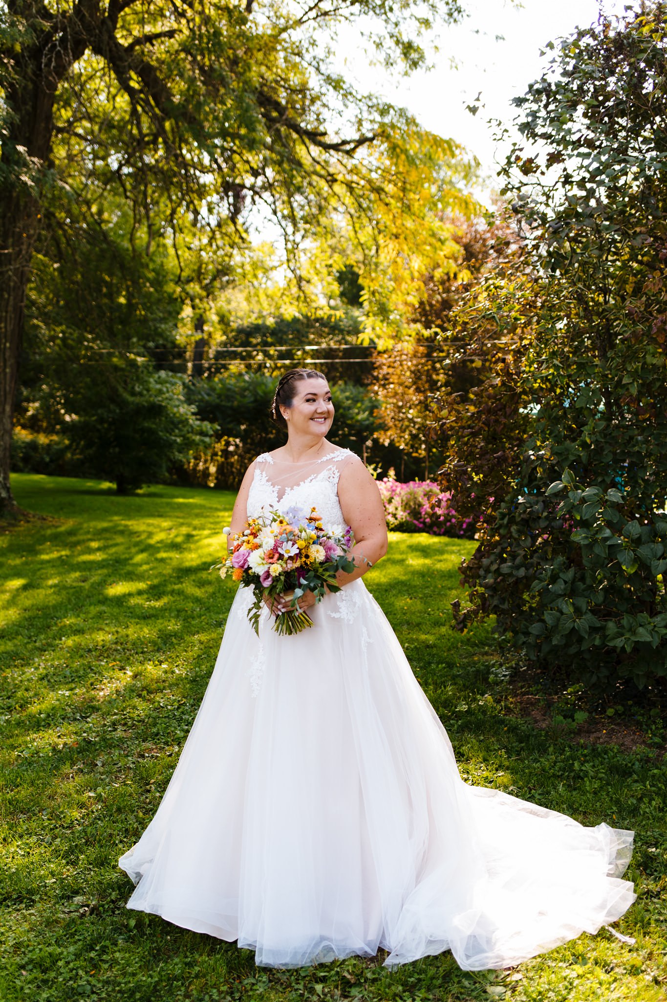 The bride smiles as she holds a colorful bouquet of flowers at her fontainebleau inn wedding.
