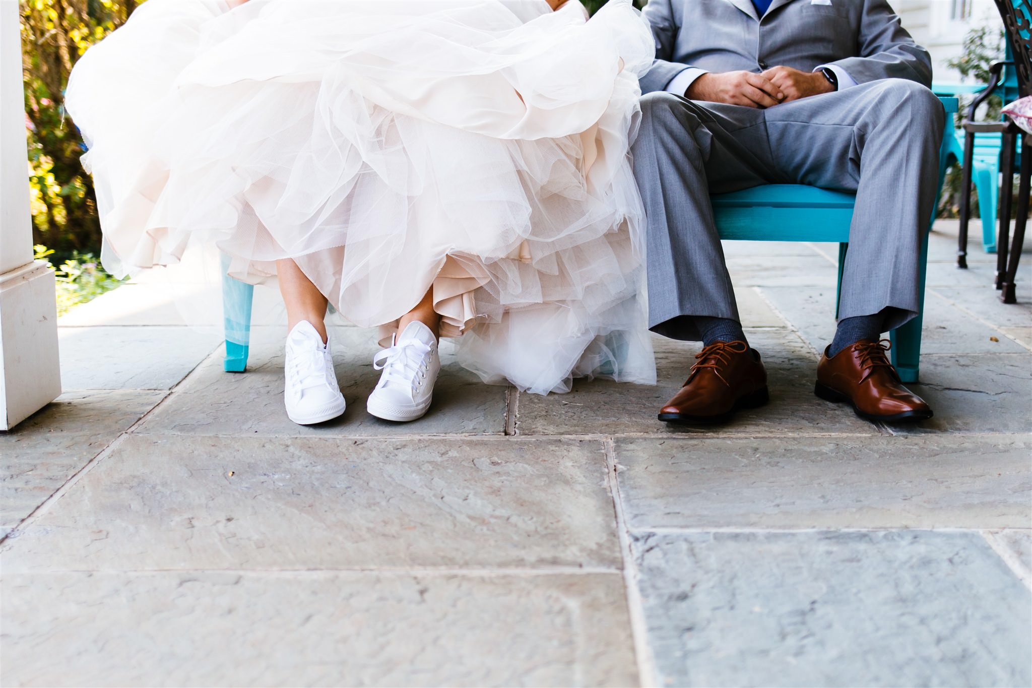 a close up of the bride and grooms footwear. The bride wears untraditional sneakers on her wedding day.