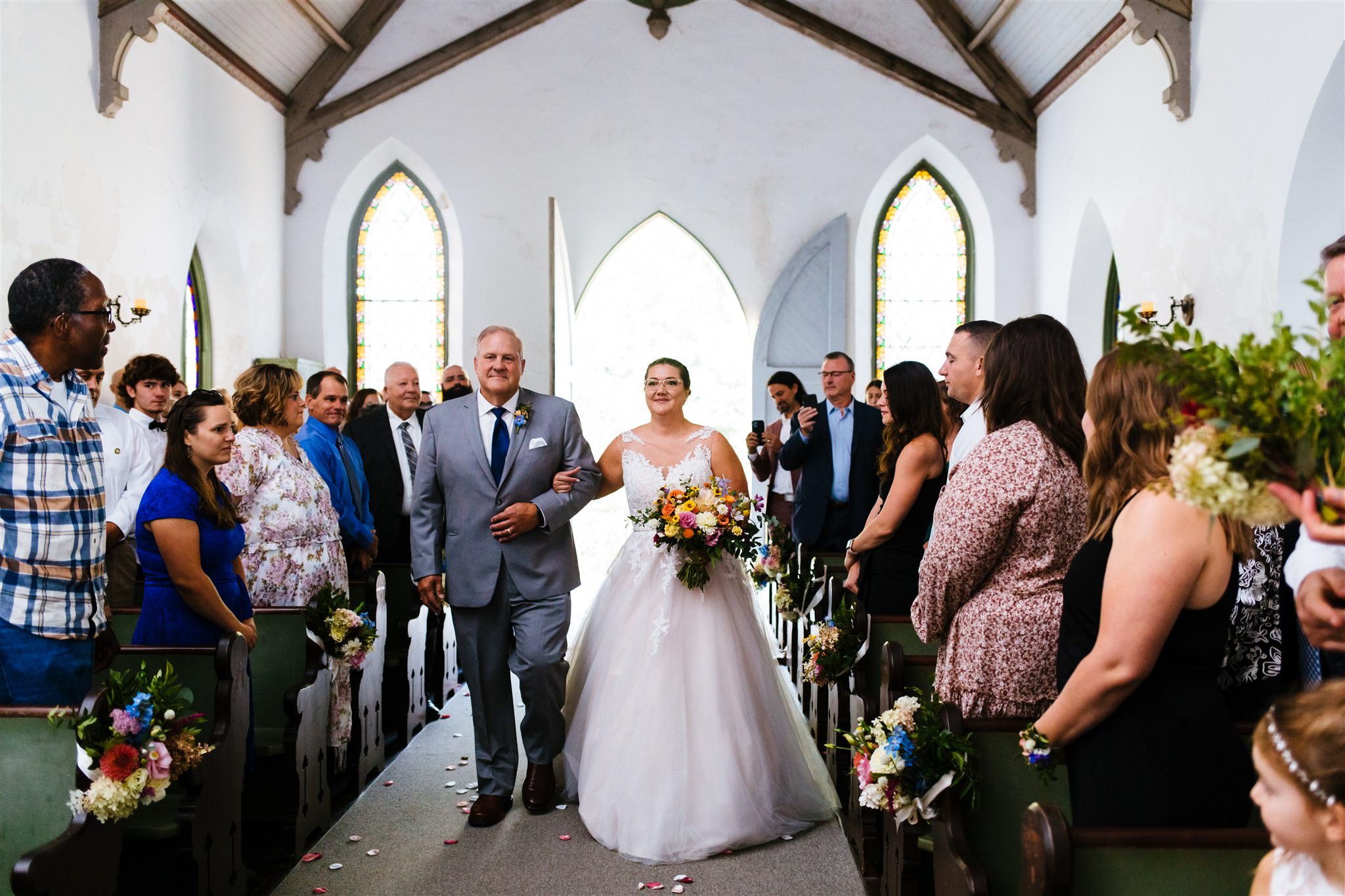 The bride walks down the aisle with her father at the small chapel at the Fontainebleau Inn in Alpine, NY.