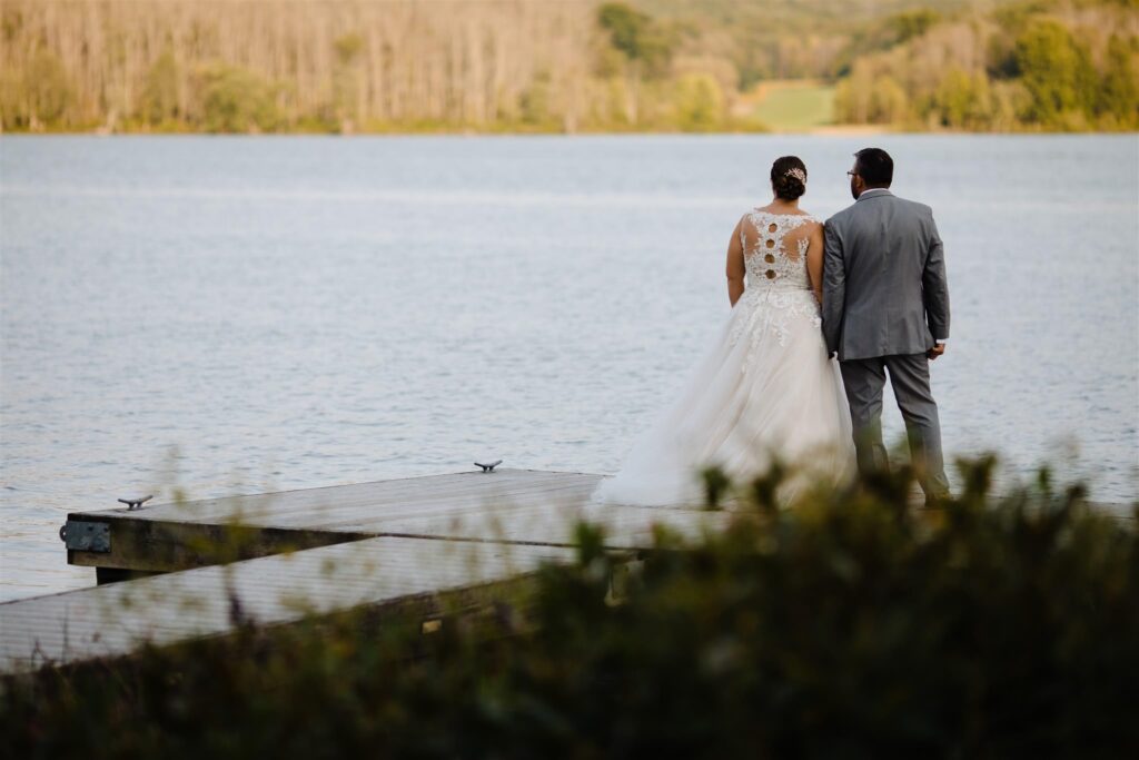 The bride and groom stand on the dock and look out at the lake at the fontainebleau Inn.