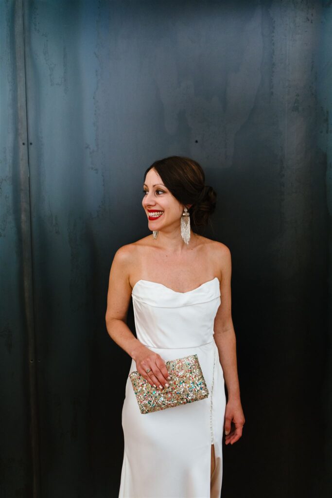 Bride wearing vintage dress and holds sequin bag at her Greylock Works wedding.