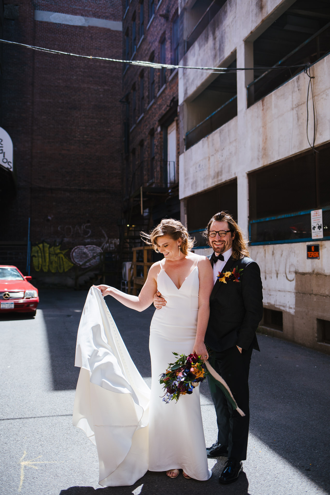 Bride and groom stand in an industrial area during their wedding photos outside of the Syracuse Gilded Club.