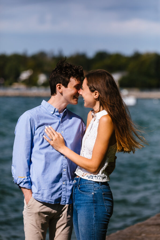 A couple laughs and leans in for a kiss after getting engaged in Skaneateles, NY.