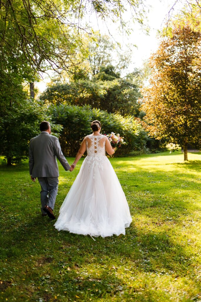 Bride and groom hold hands.