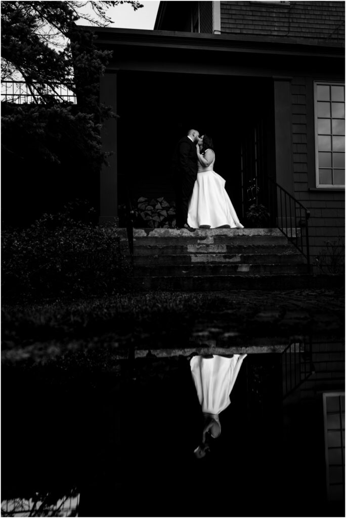 A black and white portrait of the bride and groom with their reflection in a puddle at the Sherwood Inn in Skaneateles, NY.