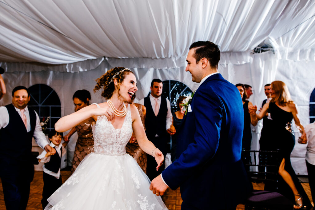 Bride and groom dance in white tent.