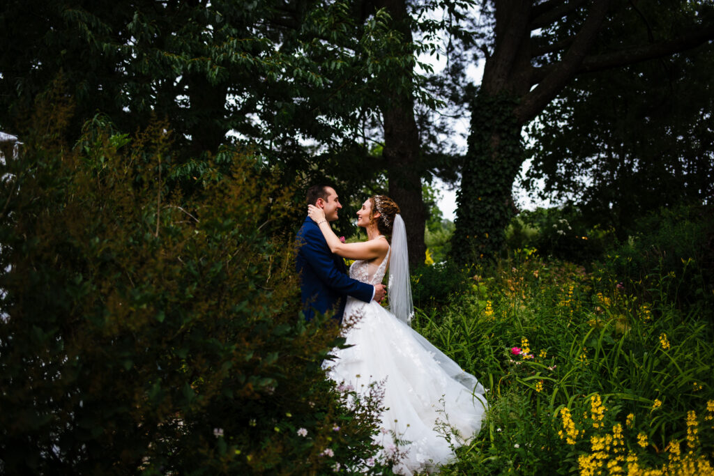 Bride and groom hug in the gardens at their finger lakes wedding. 