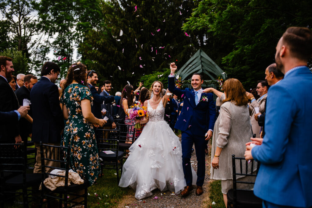 Bride and groom celebrate after their ceremony at the John Joseph Inn. Guests toss flower petals in the air.