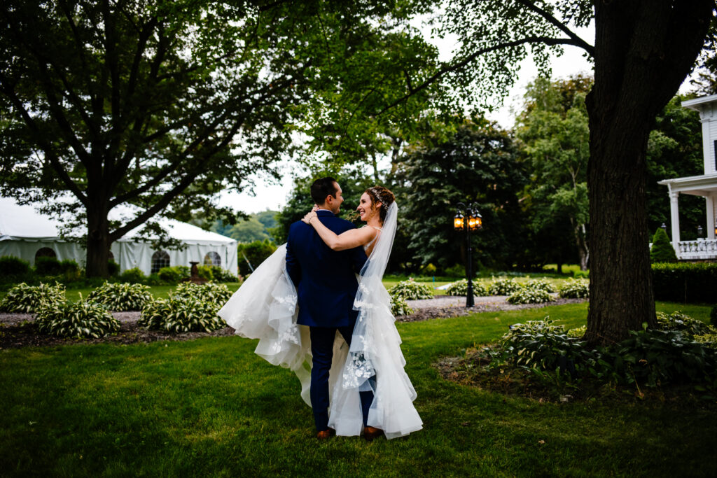 Groom holds bride in his arm on their wedding day. 