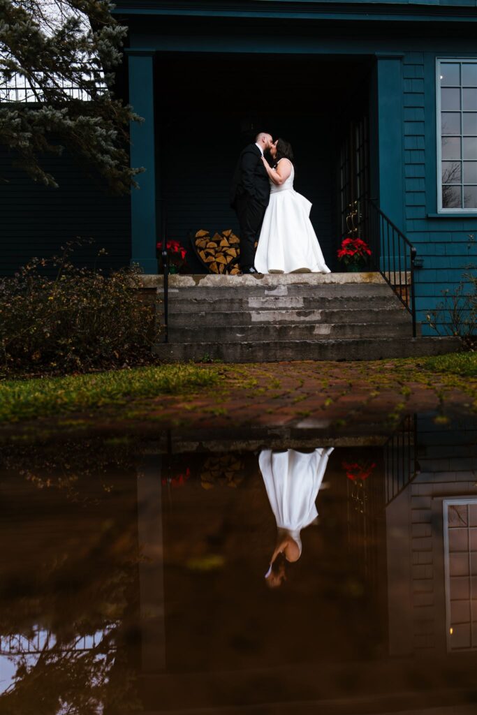 A bride and groom embrace at the sherwood inn, there is a reflection of them in the water.