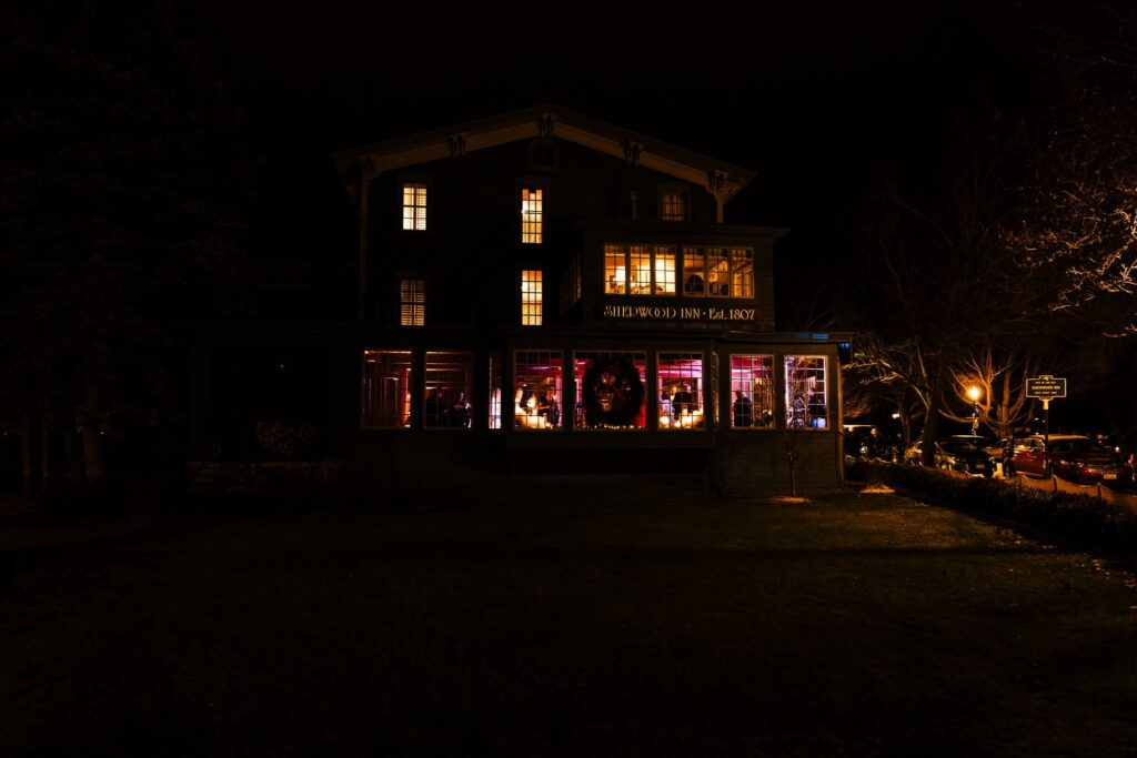 The sherwood Inn, one of many finger lakes wedding venues, is lit up from the inside with wedding lights. 