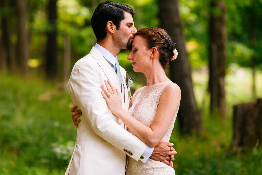 Groom kisses bride in the woods at New Park Event Venue in Ithaca, NY.