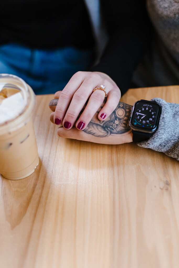 close up of the couples hands next to a coffee at Sweet Praxis in Syracuse, NY.