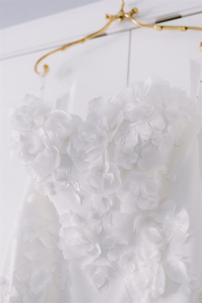 A stunning detail photo of the bride's dress with white flowers on it.