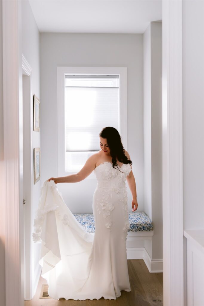 Bride holds her dress as she gets ready for her Rochester, NY wedding.