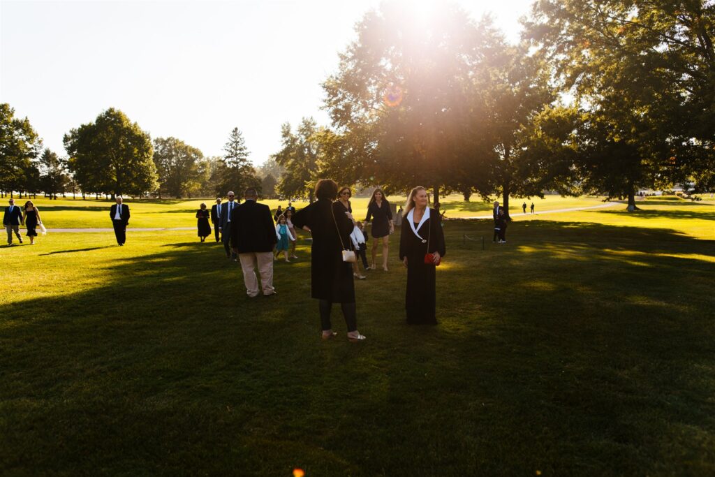 Guests mingle in golden light at Locust Hill Country Club in Rochester, NY before a wedding.