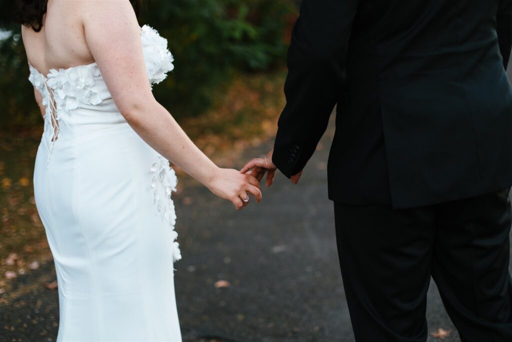 Detail photo of bride and groom holding hands.