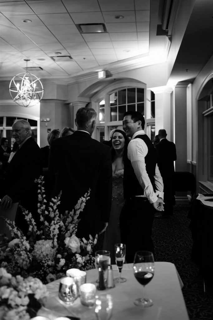 Bride and groom chat and laugh with guests at their locust hill country club wedding reception.