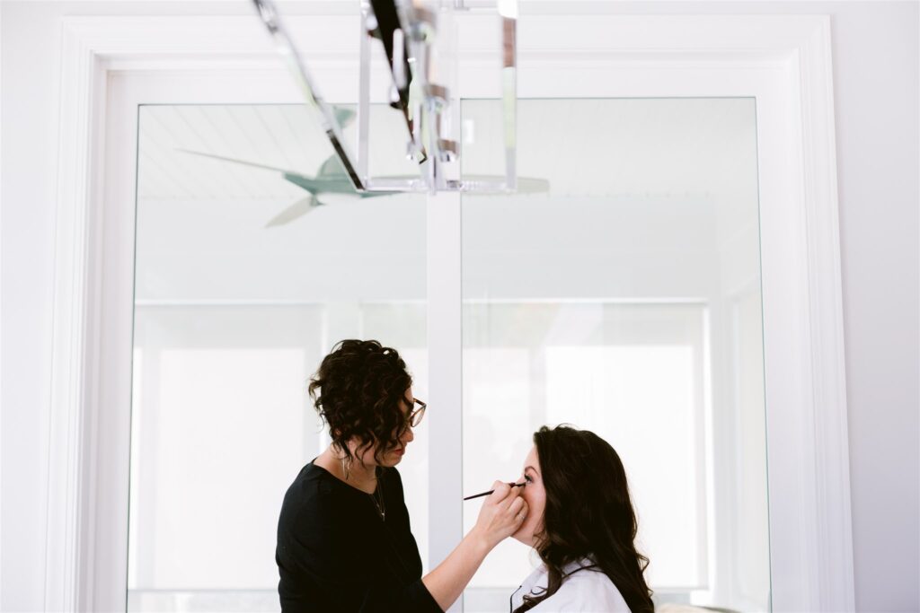 Bride gets ready before her wedding with her makeup artist from T Salon