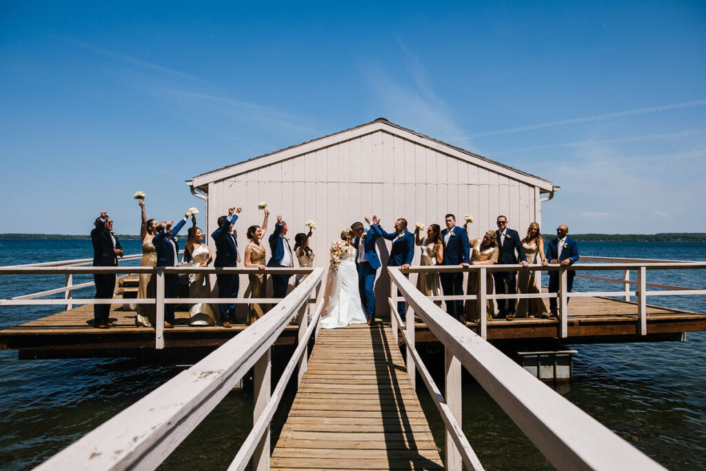 Newlyweds with their wedding party celebrating on a dock 