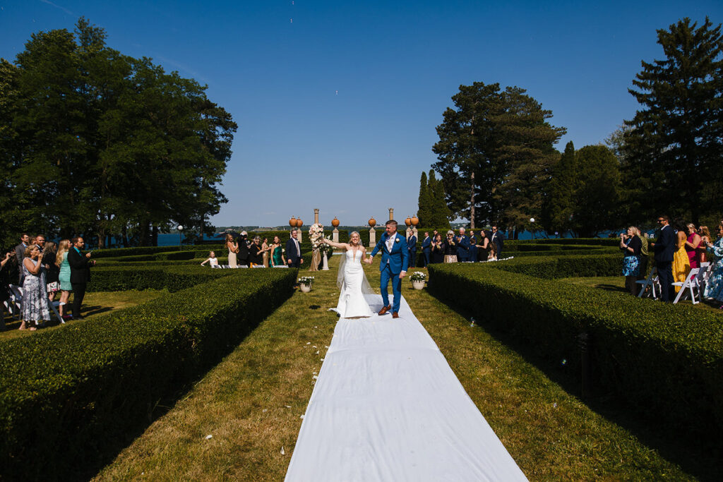 A newlywed couple walking back up the aisle in a garden wedding 