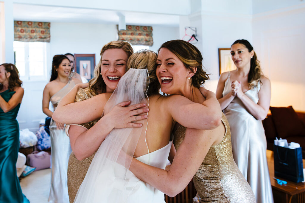 Bridesmaids smiling and hugging a bride 