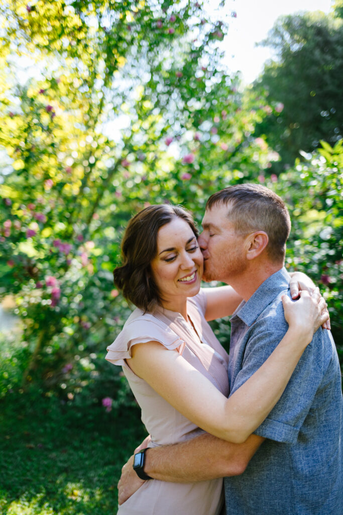 Engaged couple posing together amidst blooming flowers in Marcellus Park, Upstate New York.