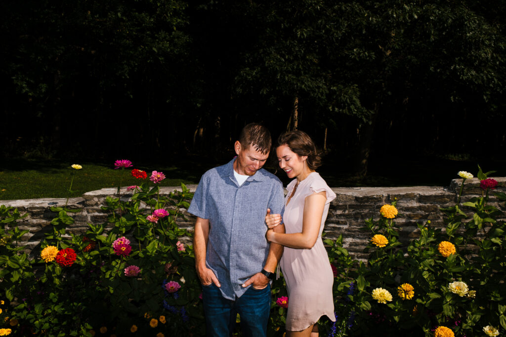 Engaged couple posing together amidst blooming flowers in Marcellus Park, Upstate New York.