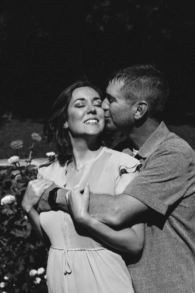 Engaged couple posing together amidst blooming flowers in Marcellus Park, Upstate New York.