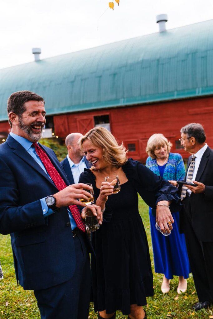 A group of wedding guests enjoy drinks and laugh together.