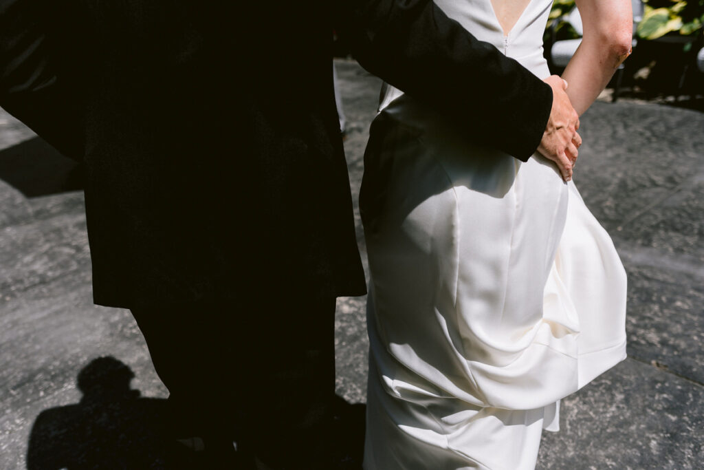 A close-up of a bride in a white dress and groom in a dark suit standing together.