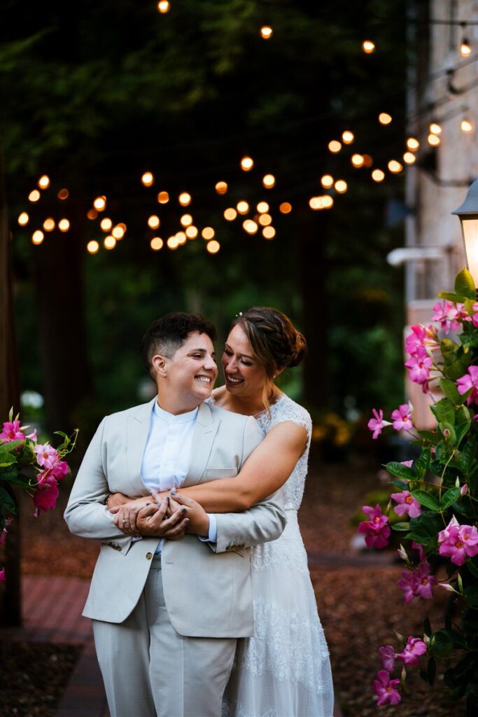 A newlywed couple with their arms around each other smiling. 