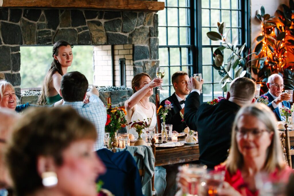 Newlyweds and wedding guests holding their glasses up during at toast at a reception 