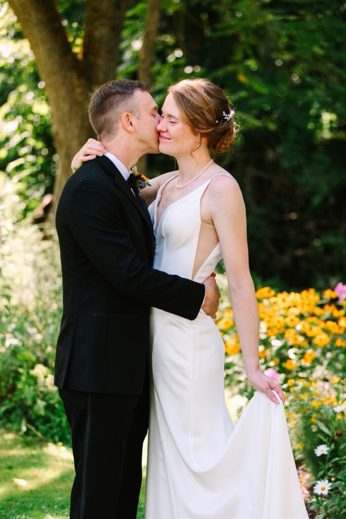 A person kissing their partner's cheek on their wedding day