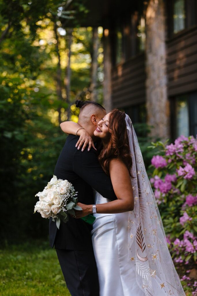 Newlyweds hugging while one is holding a bouquet of flowers 