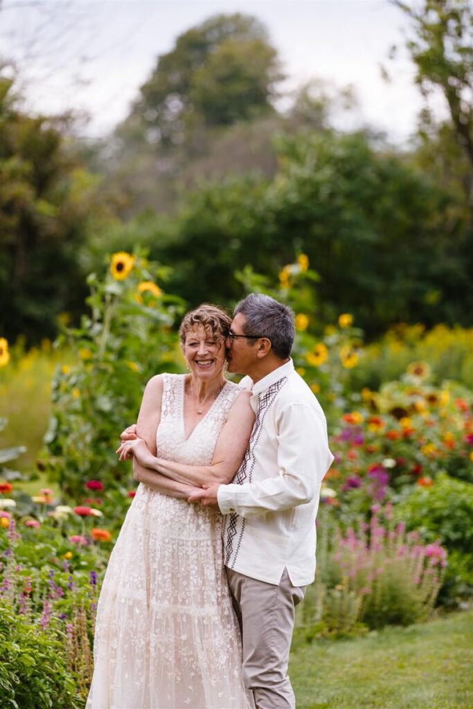 A person kissing their partner's cheek while they hug them on their wedding day