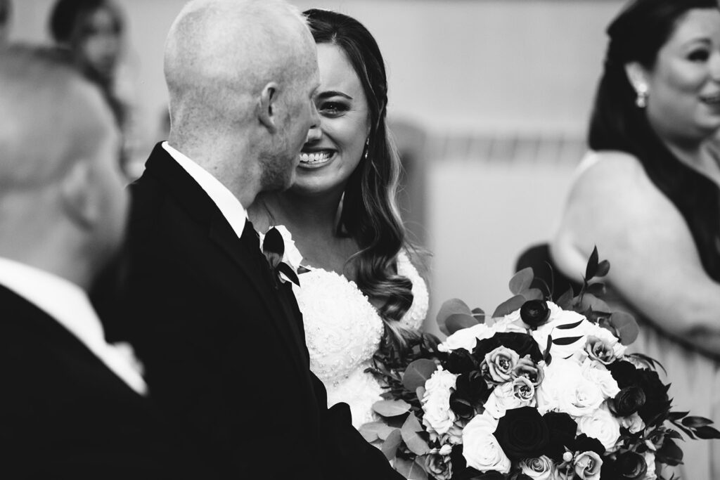 A bride turns to her groom during her catholic wedding ceremony in Syracuse, NY. Her face is full of emotion,