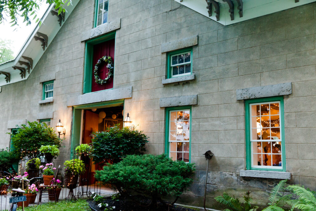 The exterior of The Frogpond, a unique building with green trim and a large floral wreath above the entrance.